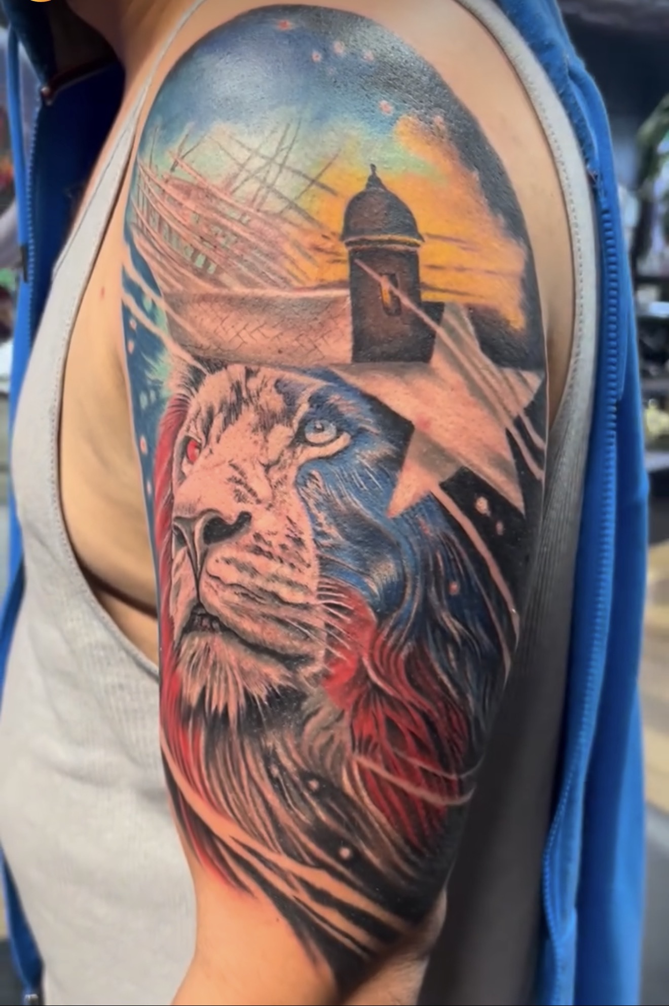 Color realism tattoo of a lion portrait fused with the Puerto Rican flag, El Morro sentry box and star